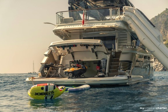 Stern of large luxury motor yacht, with water toys and big slide