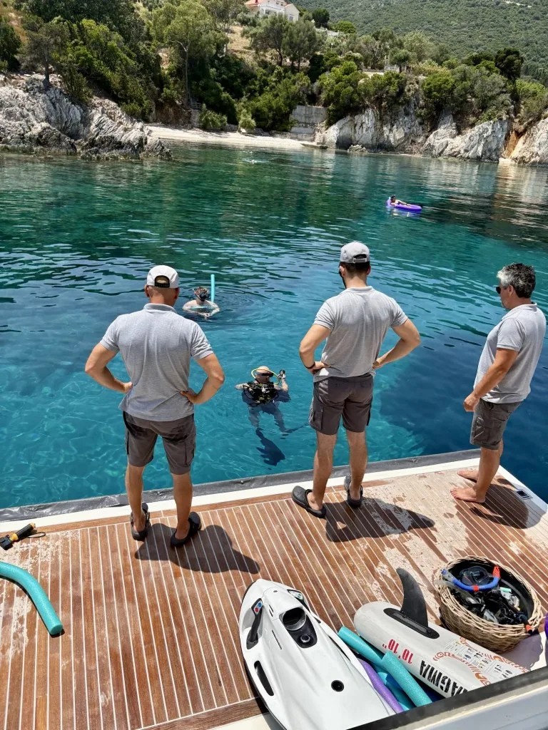crew watching guests play with water toys off the stern of the yacht