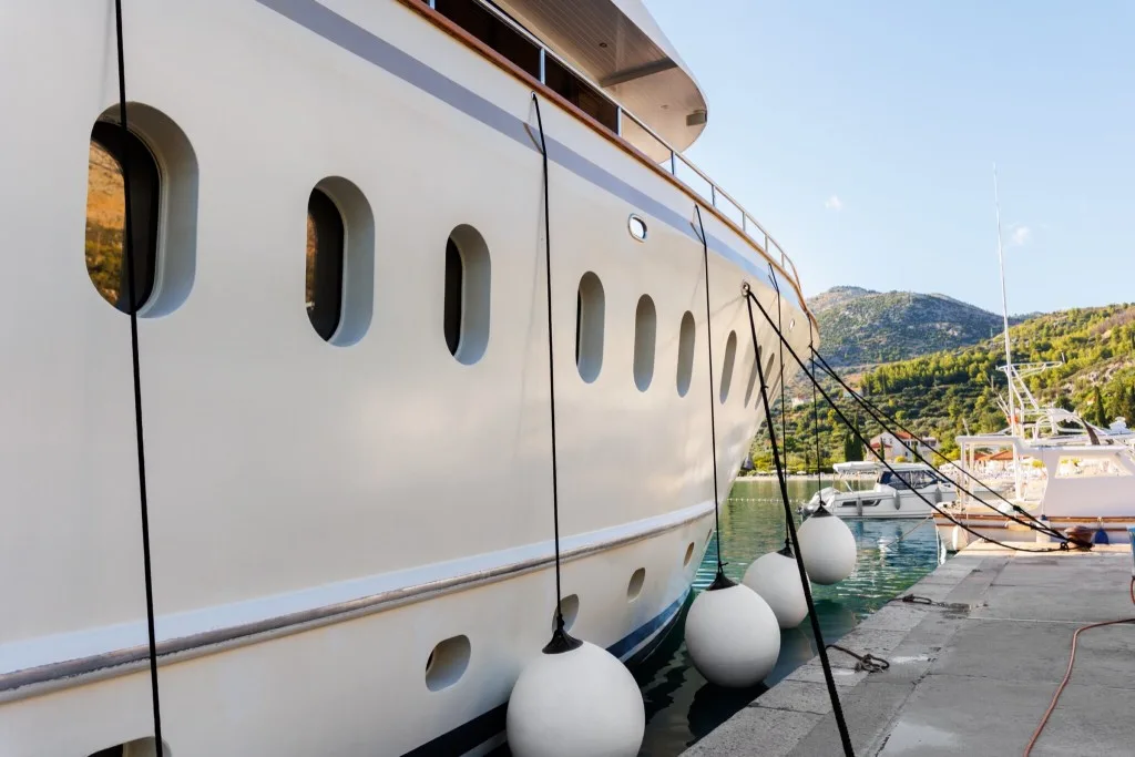 Close view of a large charter yacht lying alongside a Croatian quay at sunset, fenders out along her hull