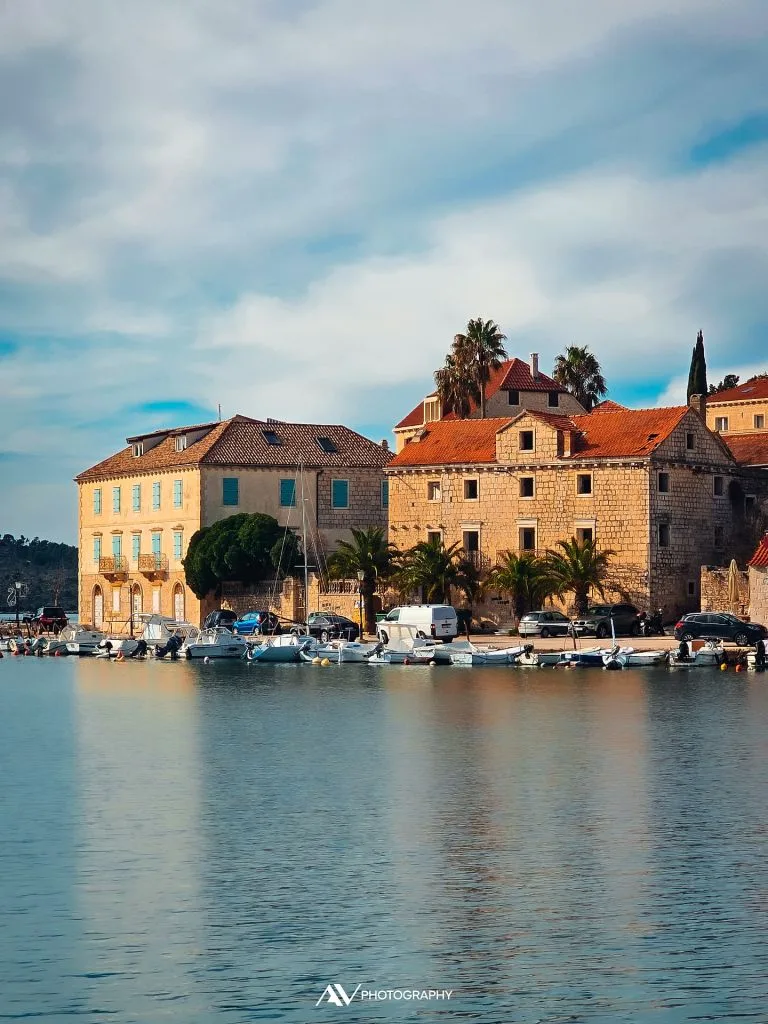Stone waterfront houses, palm trees and boats in Milna on Brač