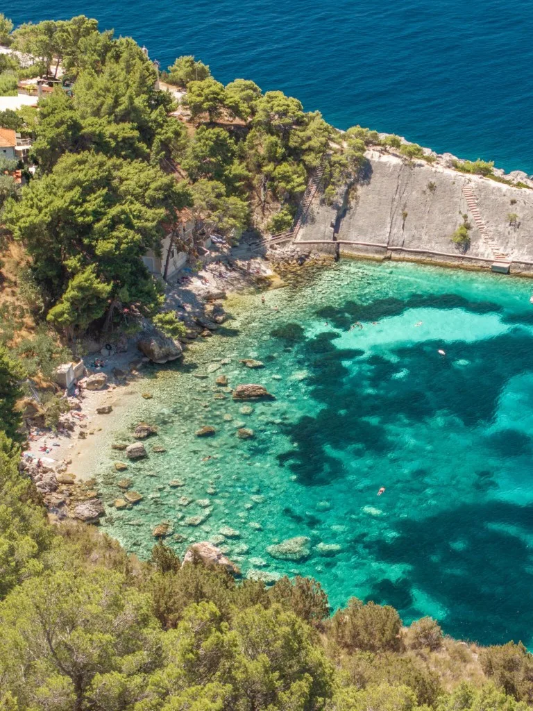 Turquoise water and wooded rocky shore at Zarače beach on Hvar
