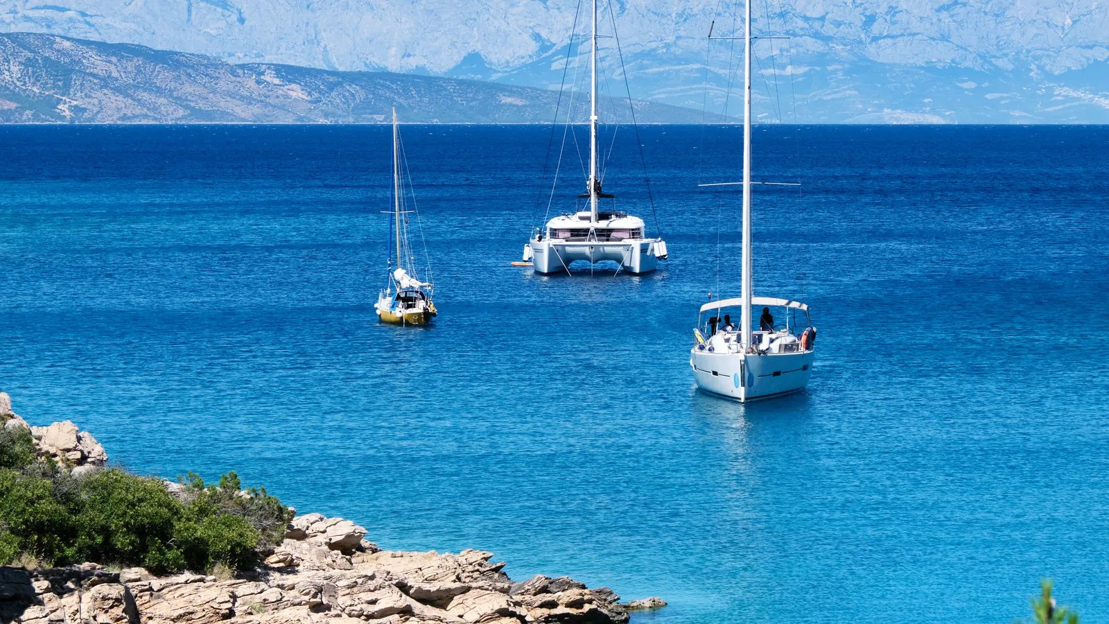 Yachts anchored off the rocky coast of Hvar in clear blue water