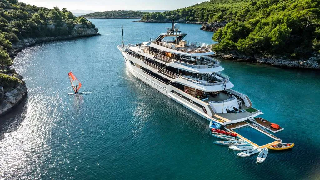 Motor yacht ARGO at anchor in a wooded Croatian bay with the sea pool and toys deployed off the stern, from the yacht's own photography.