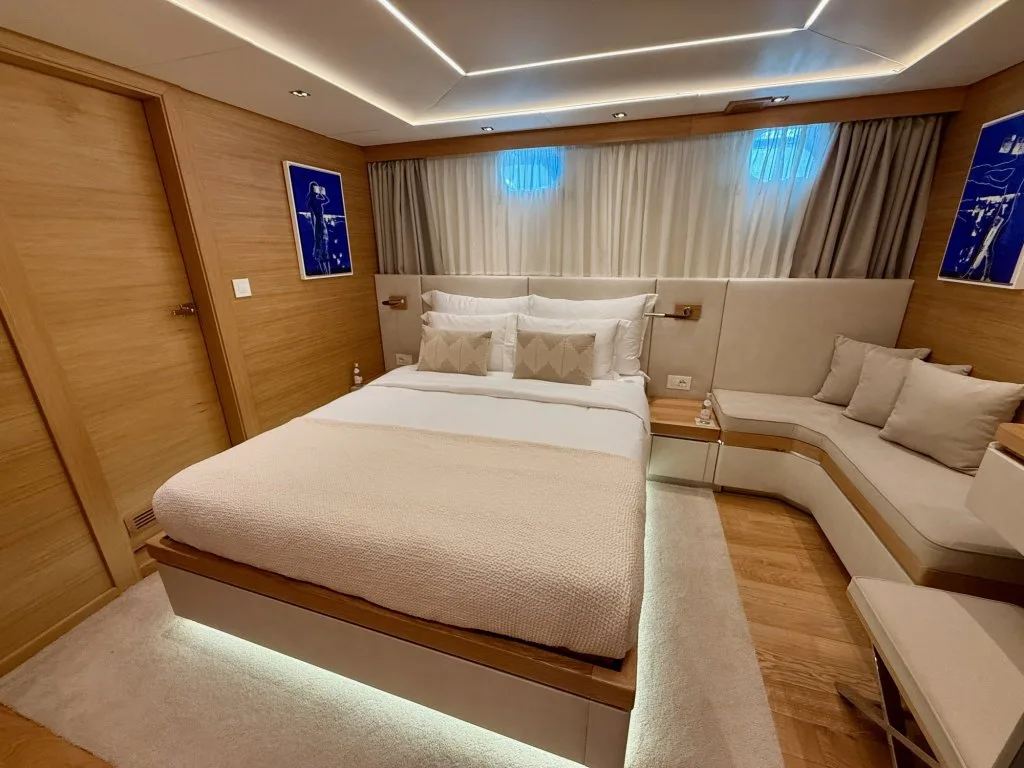 A full-beam guest suite on motor yacht ARGO with a sofa lounge and windows on both sides, September 2026.