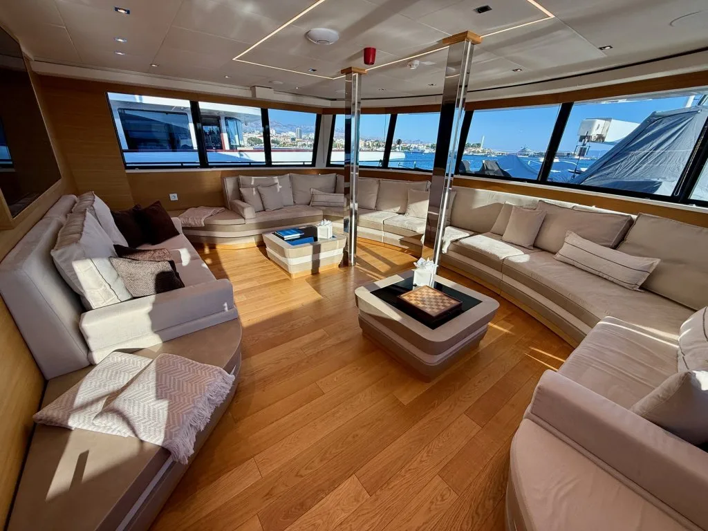 The upper saloon of motor yacht ARGO with pale sofas and windows on three sides, Split, September 2026.