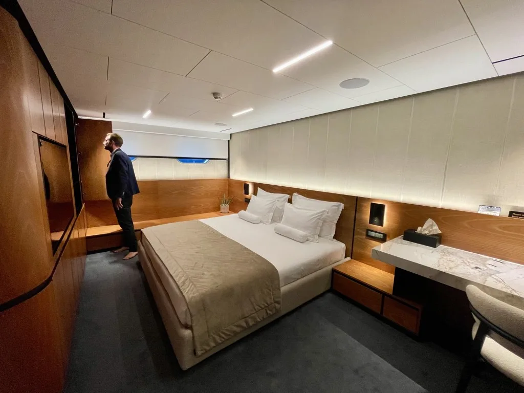 MARALLURE master cabin with the bed under the hull window and a marble vanity