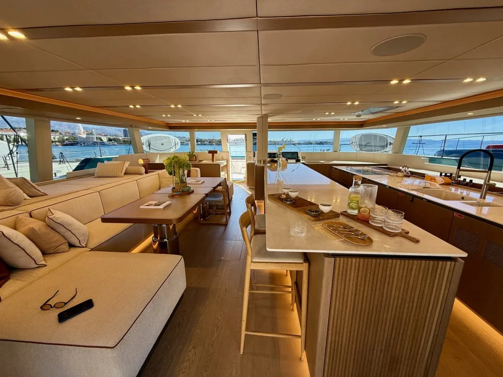 The main saloon of catamaran MIDORI with the large cooking island where the chef prepares sushi in front of guests, September 2026.