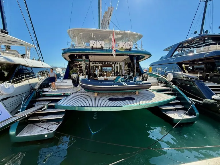 The stern of the Sunreef 70 Eco catamaran MIDORI alongside at the CROYA Yacht Charter Show in Split, deep green hull, tender on the platform, September 2026.