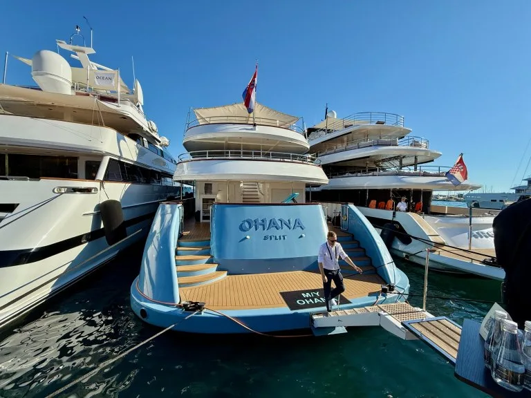 The stern of the 49-metre motor yacht OHANA alongside at the CROYA Yacht Charter Show in Split, with her name on the transom and the swim platform down, September 2026.