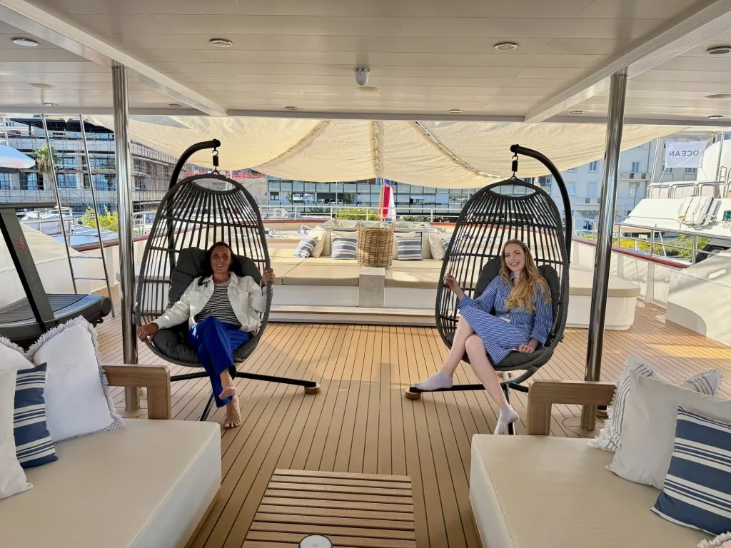 Two rattan hanging chairs on the sun deck of motor yacht OHANA, with DMA team members sitting in them during the CROYA show, September 2026.