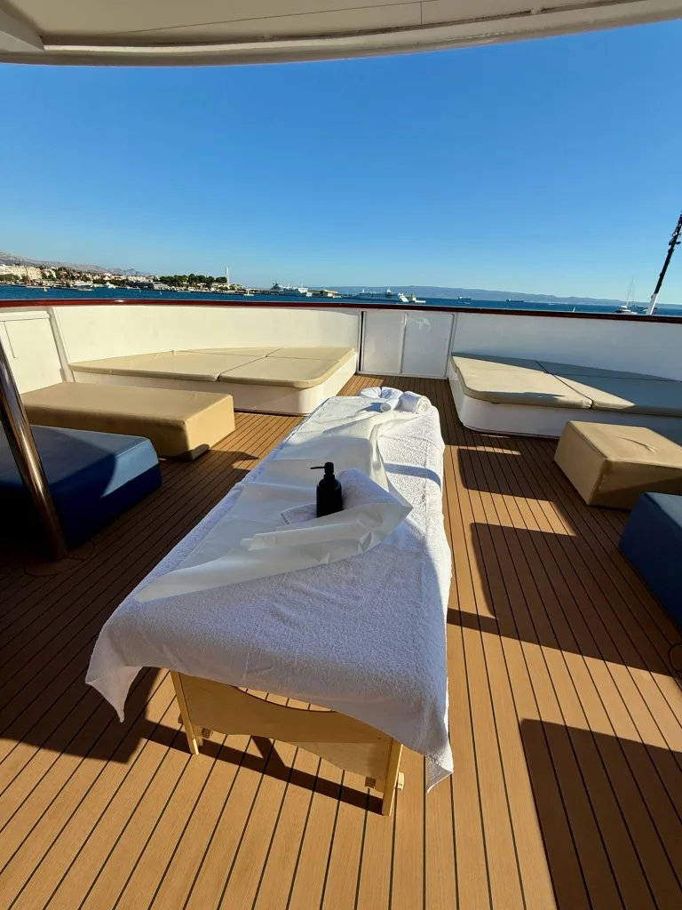 A massage table set up on the sun deck of motor yacht OHANA with the sea behind, September 2026.