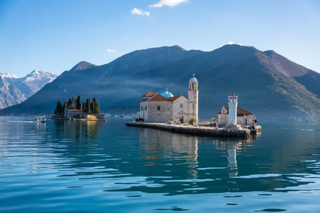 Our Lady of the Rocks church islet seen from the water in the Bay of Kotor, Montenegro, snow on the mountains behind