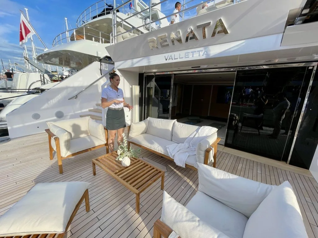 The stern beach deck of motor yacht RENATA with a white sofa and coffee table and the name on the transom above, October 2025.