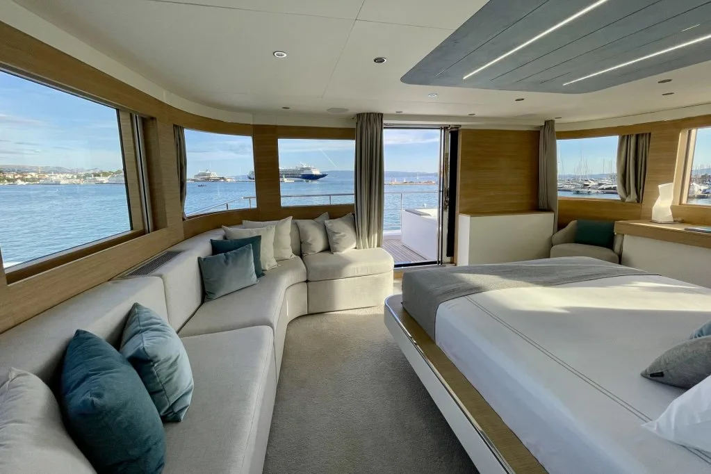The master cabin on motor yacht RENATA with wraparound windows and the door open to the private balcony, September 2026.