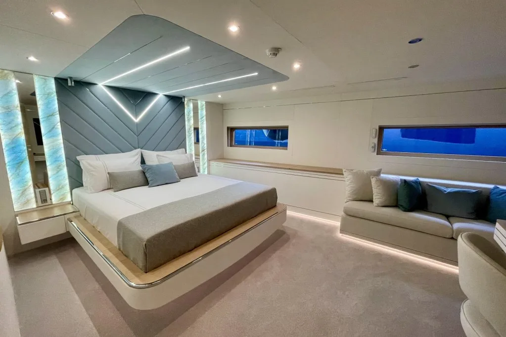 A VIP guest cabin on motor yacht RENATA with a wide bed, pale fabrics, LED-lit headboard and a sofa under the windows, September 2026.