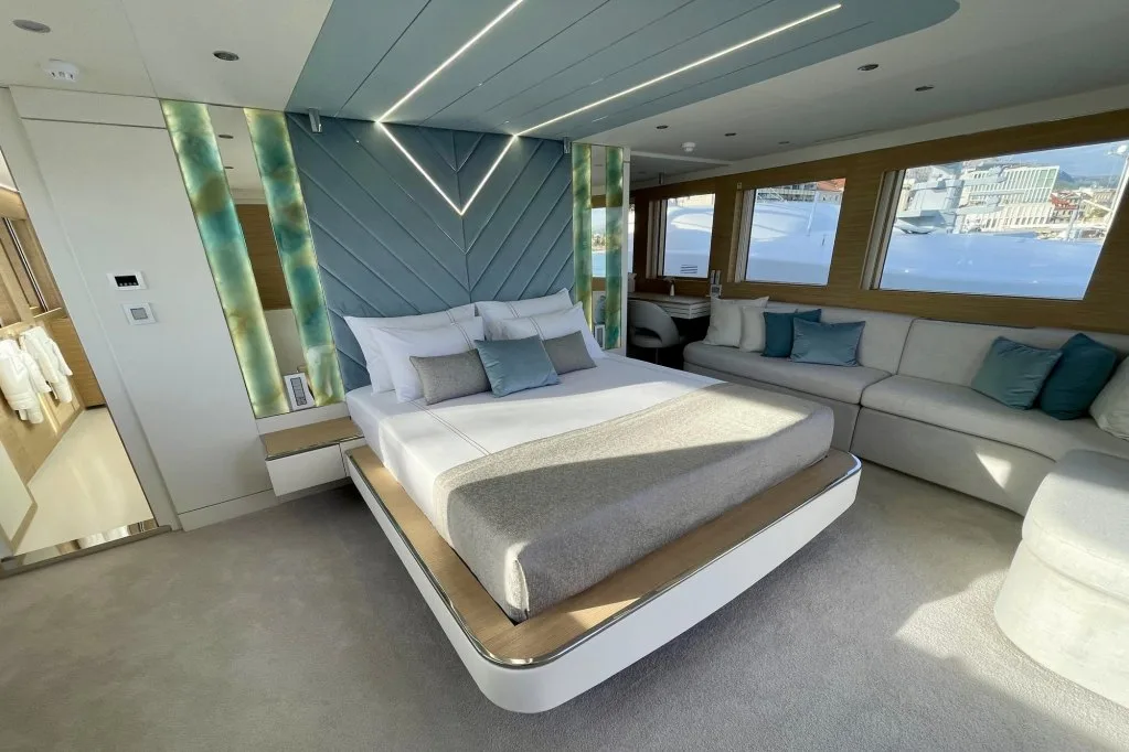 The second VIP guest cabin on motor yacht RENATA, with the bed set against a lit chevron headboard and a lounge by the windows, September 2026.