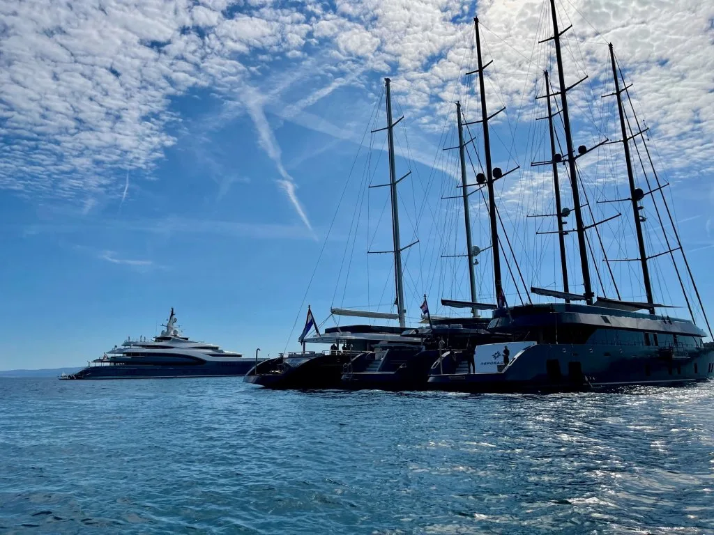 Three Tramontana motorsailers, REPOSADO among them, rafted at anchor off Split with the coast behind, September 2025.