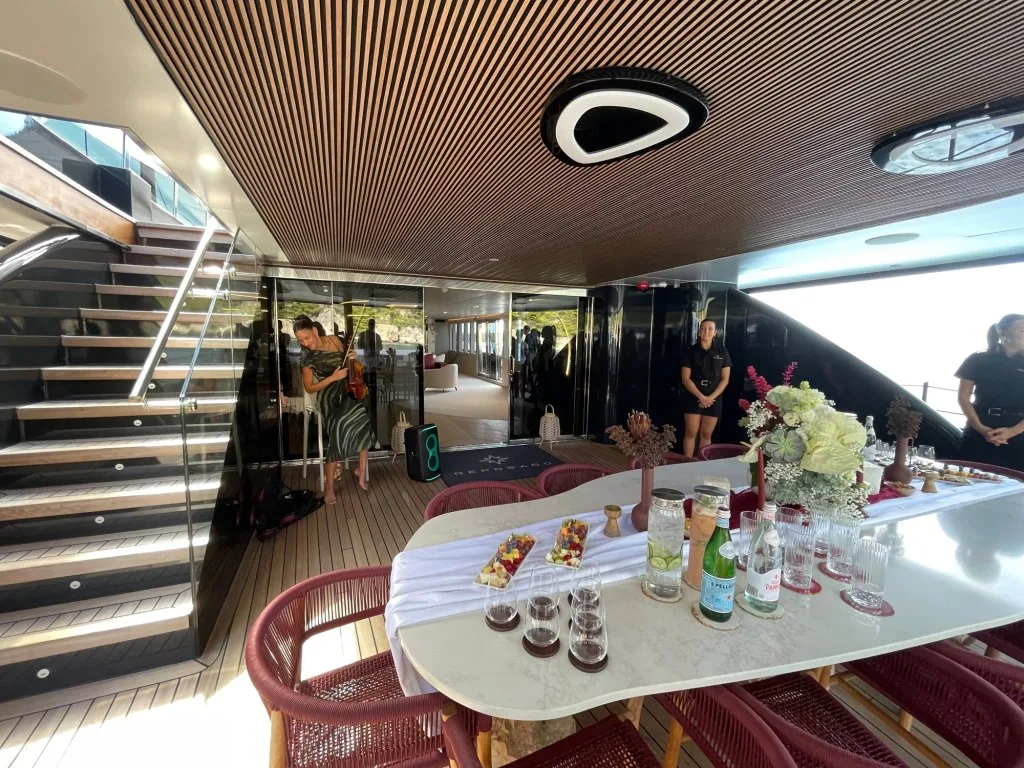 The saloon of motorsailer REPOSADO seen from the staircase, with a marble table laid for the show lunch, September 2025.
